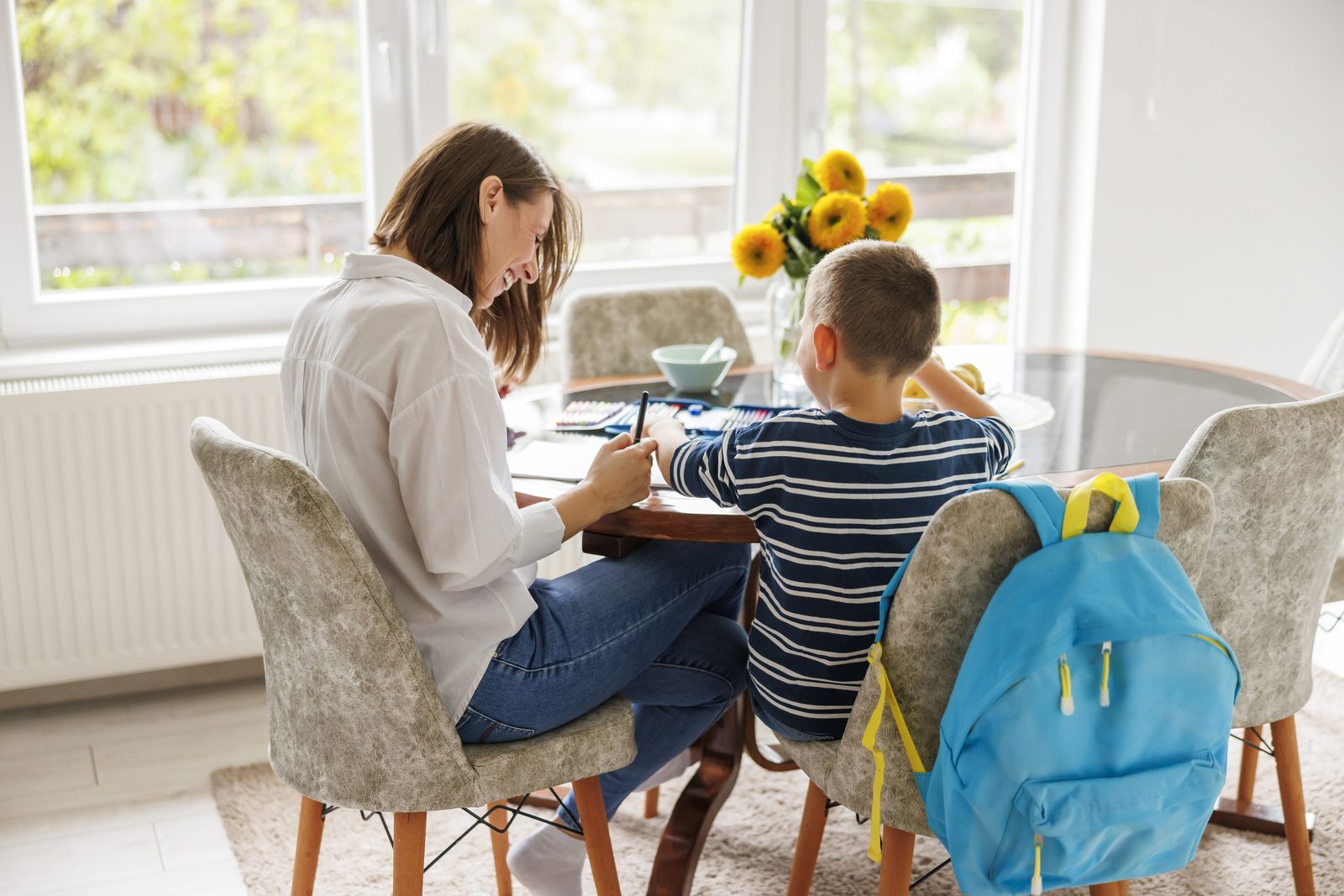 A parent doing school work with her child at the table